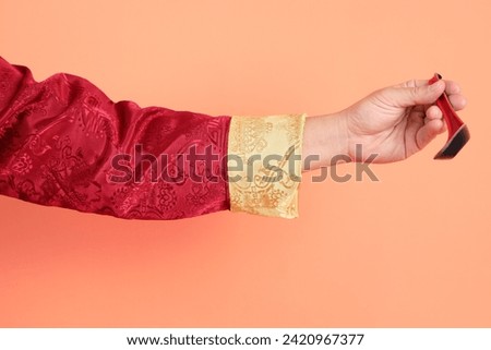 Happy Chinese new year. Hand of asian chinese senior man wearing red traditional clothing with gesture of hand holding spoon isolated on orange background.