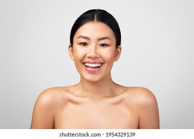 Happy Chinese Young Woman Posing Smiling To Camera Standing Shirtless Over Gray Studio Background. Headshot Portrait Of Cheerful Chinese Female Expressing Positive Emotion. Natural Beauty Concept