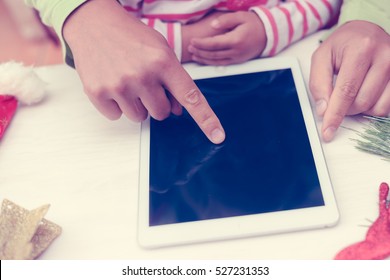 Happy Christmas background. Top view on father and child hands using tablet computer with toys and Santa Claus hat on light wooden table. Festive decoration ready for joyful message or shopping time - Powered by Shutterstock