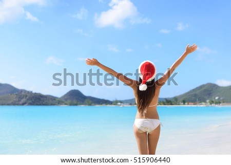 Happy Christmas holiday santa hat woman on beach vacation winning arms up in success.