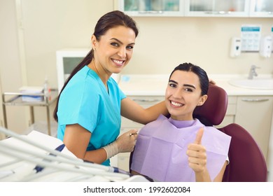 Happy client in dentist's office recommending dental clinic satisfied with good service provided by hygienist. Smiling female patient giving thumbs up and looking at camera during regular checkup - Shutterstock ID 1992602084