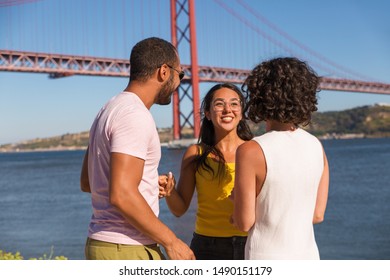 Happy Close Friends Sharing Good News Outdoors. Excited Man And Women Standing Near River, Holding Hands, Talking, Chatting, Smiling And Laughing. Group Of Close Friends Concept