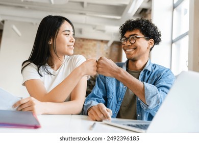 Happy colleagues business partners friends college students classmates giving fist bump while working studding doing home work create start up project together at the working desk in office cafe - Powered by Shutterstock