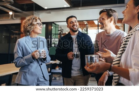 Happy colleagues having a coffee break in an office. Group of business people having a conversation in a workplace. Business professionals working in a startup.