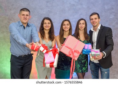 Happy colleagues with present boxes posing on abstract background