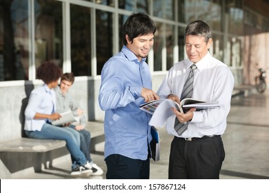 Happy College Professor With Books Explaining Student On Campus