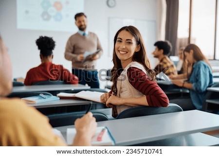 Happy college student during a lecture in the classroom looking at camera.