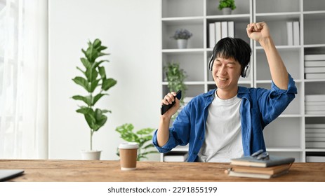 Happy college student listening to music with headphone while using smartphone in the study room. - Shutterstock ID 2291855199