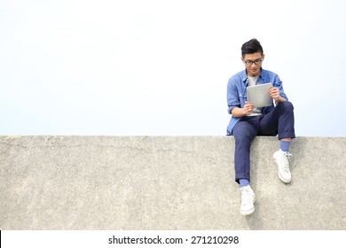 Happy College student man using digital tablet pc and sit, asian male