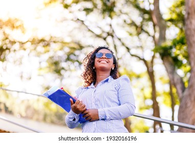 Happy College Student Walking Down Stairs On College Campus And Holding Folders And Notebooks.