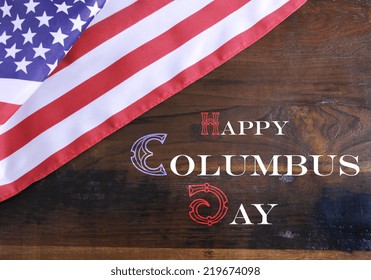 Happy Columbus Day greeting message text on dark rustic recycled wood background with USA stars and stripes flag.