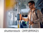 Happy commuter paying with smart phone while onboarding in public transport.