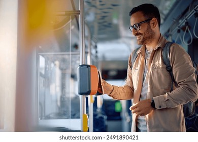 Happy commuter paying with smart phone while onboarding in public transport. - Powered by Shutterstock