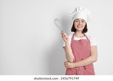 Happy confectioner holding whisk on light grey background, space for text - Powered by Shutterstock