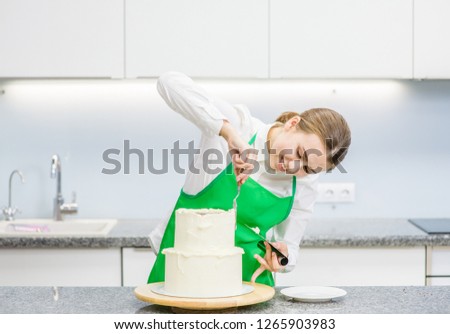 Happy confectioner makes a wedding cake with white cream  using a  cooking spatula 