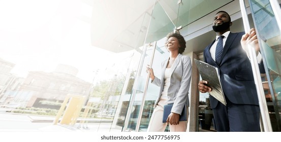 Happy confident african american business people walking out of modern office center after successful meeting. Low-Angle Shot with copy space - Powered by Shutterstock