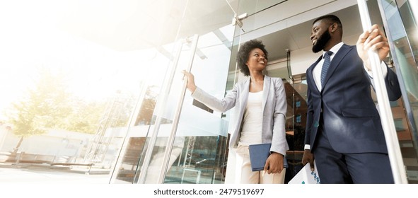 Happy confident african american business people walking out of modern office center after successful meeting. Low-Angle shot with copy space - Powered by Shutterstock