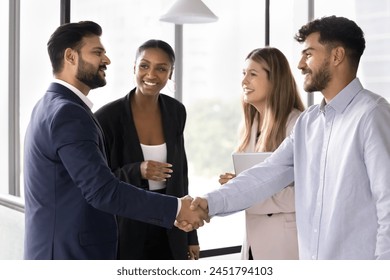 Happy confident diverse male business partners shaking hands at meeting, standing in office hall, closing deal, getting agreement, finishing successful work project with handshake - Powered by Shutterstock