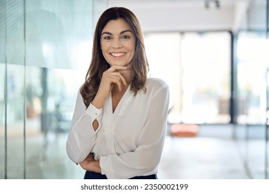 Happy confident Latin professional mid aged business woman in office, portrait. Smiling lady corporate leader, mature female executive, lady manager standing in looking at camera, portrait. - Powered by Shutterstock