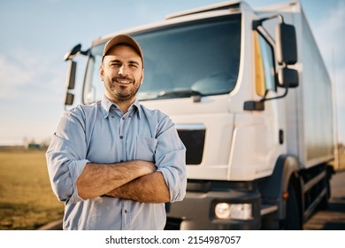 Happy confident male driver standing in front on his truck and looking at camera.