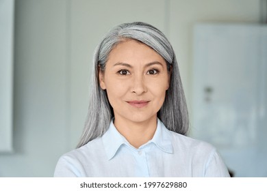 Happy confident middle aged Asian older senior female lawyer businesswoman corporation ceo in modern office looking at camera. Business woman executive concept. Closeup portrait headshot.