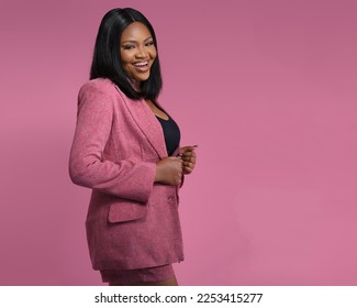 Happy confident professional posing Over a Pink Background. Young African American business woman  adjusting formal jacket, looking at camera, smiling. Successful businesswoman concept - Powered by Shutterstock