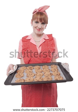 Happy confident vintage style housewife holding an oven tray with freshly baked cookies