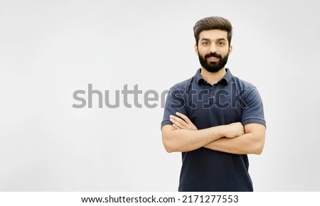 Happy Confident young bearded man standing with crossed arms on white background with copy space on the left side - Pakistani Indian South Asian Arabic Middle Eastern