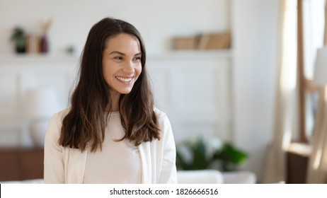 Happy confident young female owner, buyer or tenant of new flat standing in living room alone and looking aside with cheerful white smile feeling independent and free resting at home, copy space - Shutterstock ID 1826666516