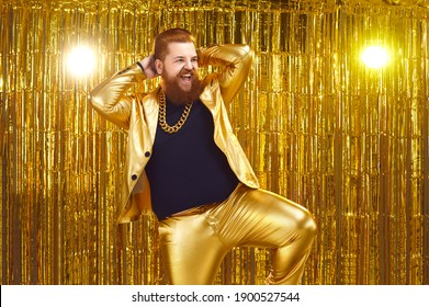 Happy Confident Young Man With Ginger Beard And Mustache Wearing Funny Golden Suit With Bling Gold Chain Necklace Performing On Stage At Night Club Disco Party, Dancing, Singing Songs And Having Fun