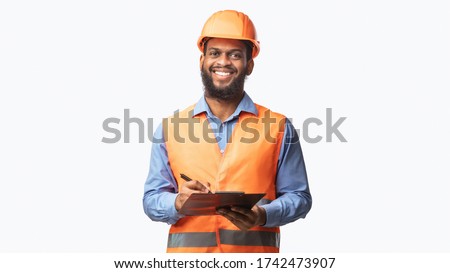Happy Construction Site Worker Guy Taking Notes Holding Folder Smiling To Camera Standing On White Background. Studio Shot, Panorama
