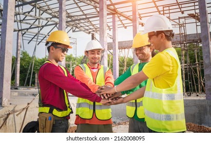 The Happy Construction Team Joins Hands To Show Unity Power And Success. Architect And Engineer Construction Workers Join Hands While Working At Outdoor Construction Sites. Teamwork Concept.