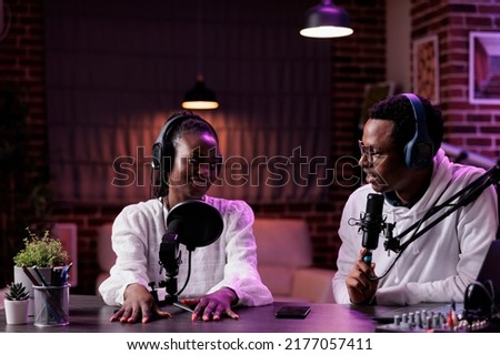 Happy content creators chatting on podcast talk show, recording live content with sound equipment in studio. Man and woman broadcasting online discussion for channel audience.