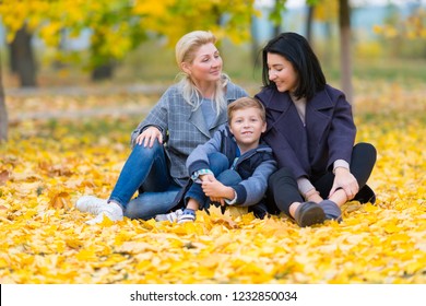 A Happy, Content Same Sex Female Couple And Their Son In A Happy Family Theme With Yellow Fall Leaves.