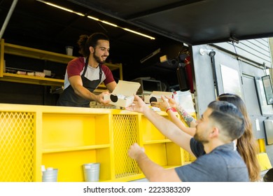 Happy cook working and serving fast food to a couple of customers at the food truck - Powered by Shutterstock