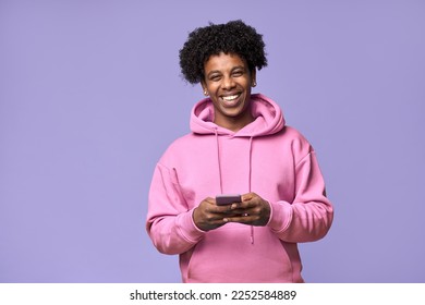 Happy cool curly African American teen guy model wearing pink hoodie holding cell phone using mobile digital apps on cellphone tech texting on smartphone isolated on light purple background. - Powered by Shutterstock