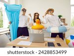 Happy corporate business team going on summer vacation together. Group of three cheerful, excited, young people, ready for holiday, with inflatable toys and water mattress having fun in the office