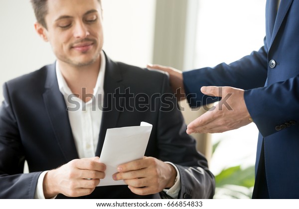 Happy corrupted businessman accepting bribe, male hand\
giving smiling office worker envelope salary at workplace,\
receiving business letter, bonus for good work, bribery and\
corruption concept 