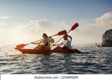 Happy coulple walks by sea kayak or canoe at sunset bay. Kayaking or canoeing concept with people - Powered by Shutterstock