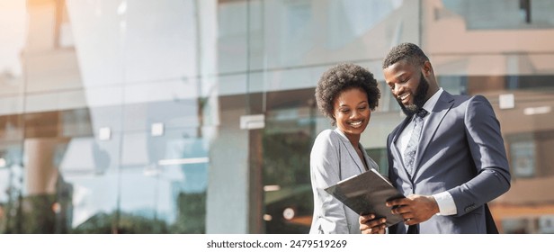 Happy couple of african american business partners working while standing outdoors, discussing new project. Blurred background with copy space - Powered by Shutterstock