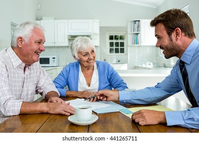 Happy couple with agent while sitting at table in home