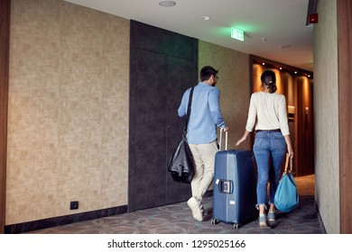 Happy Couple Arriving At Hotel Lobby With Suitcase
