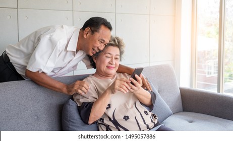 Happy couple asian senior retired using mobile tablet application technology for social network or social distancing community via internet digital communication to other person.
