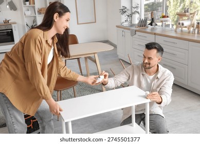Happy couple assembling shelf unit in kitchen