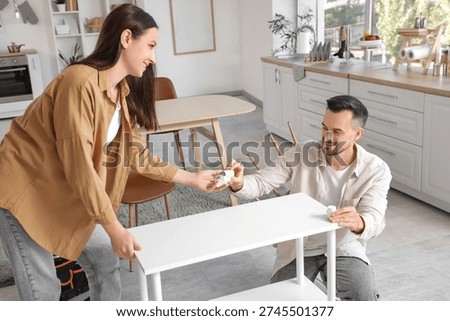 Happy couple assembling shelf unit in kitchen