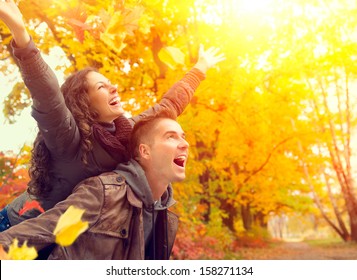 Happy Couple in Autumn Park. Fall. Young Family Having Fun Outdoors. Yellow Trees and Leaves. Laughing Man and Woman outside. Freedom Concept. - Powered by Shutterstock