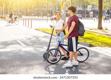 Happy couple in Barcelona going to seaside with bike and scooter - Laughing man and woman walking and pushing bike and electric scooter - Lifestyle, travel and love concepts, hot summer day in Spain - Powered by Shutterstock