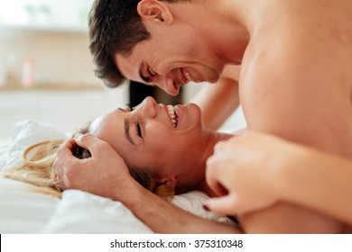 Happy couple in bedroom enjoying sensual foreplay