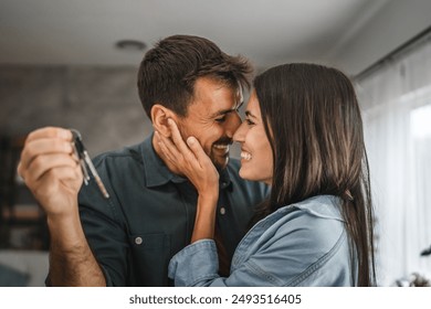 Happy couple boyfriend and girlfriend hug hold key of their new home