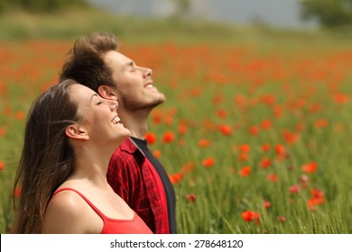 Happy Couple Breathing Fresh Air In A Colorful Field With Red Poppy Flowers